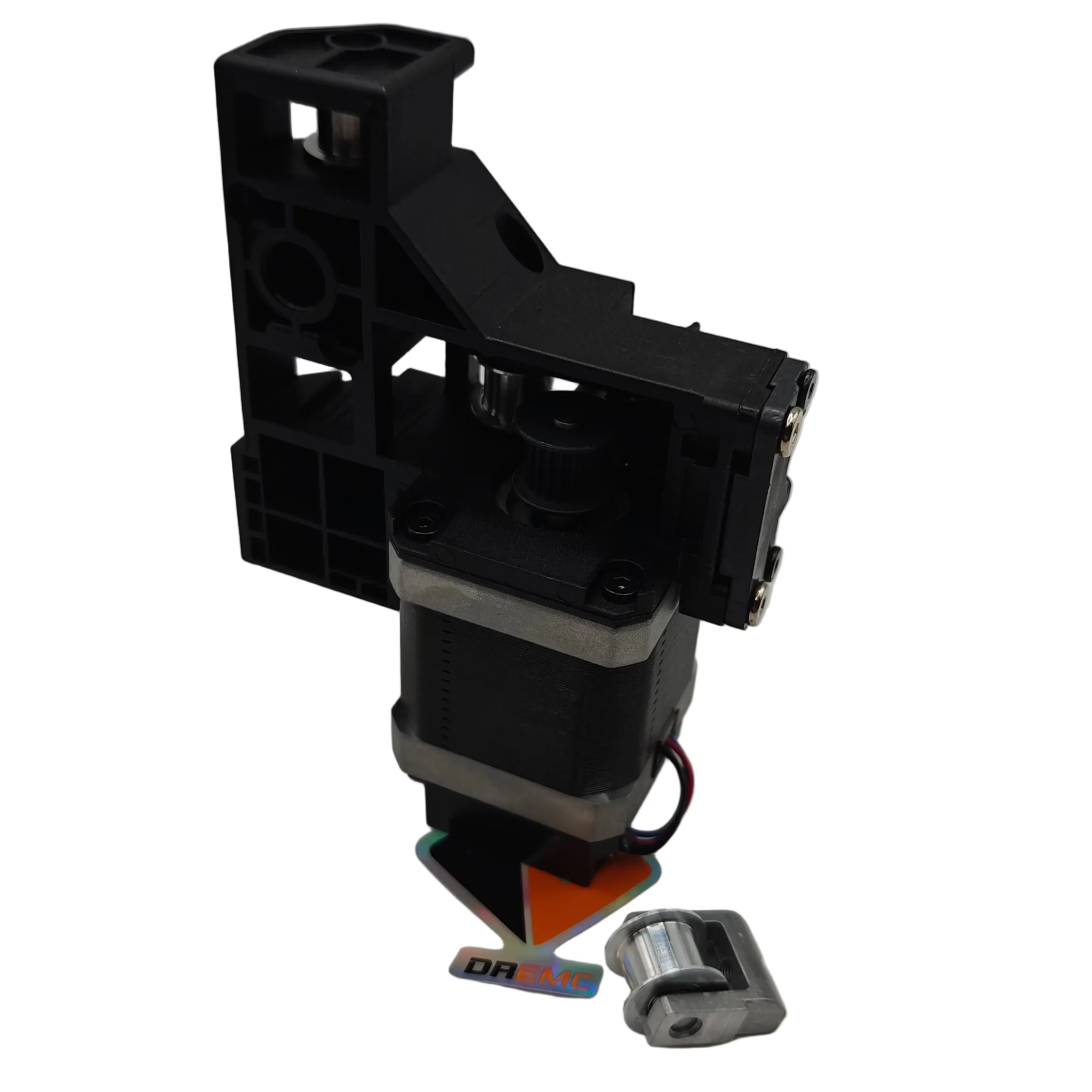 A black plastic and metal mechanical component, likely a motor or pump part, shown on a neutral gray background with a small metal piece and colorful paper pieces in front.
