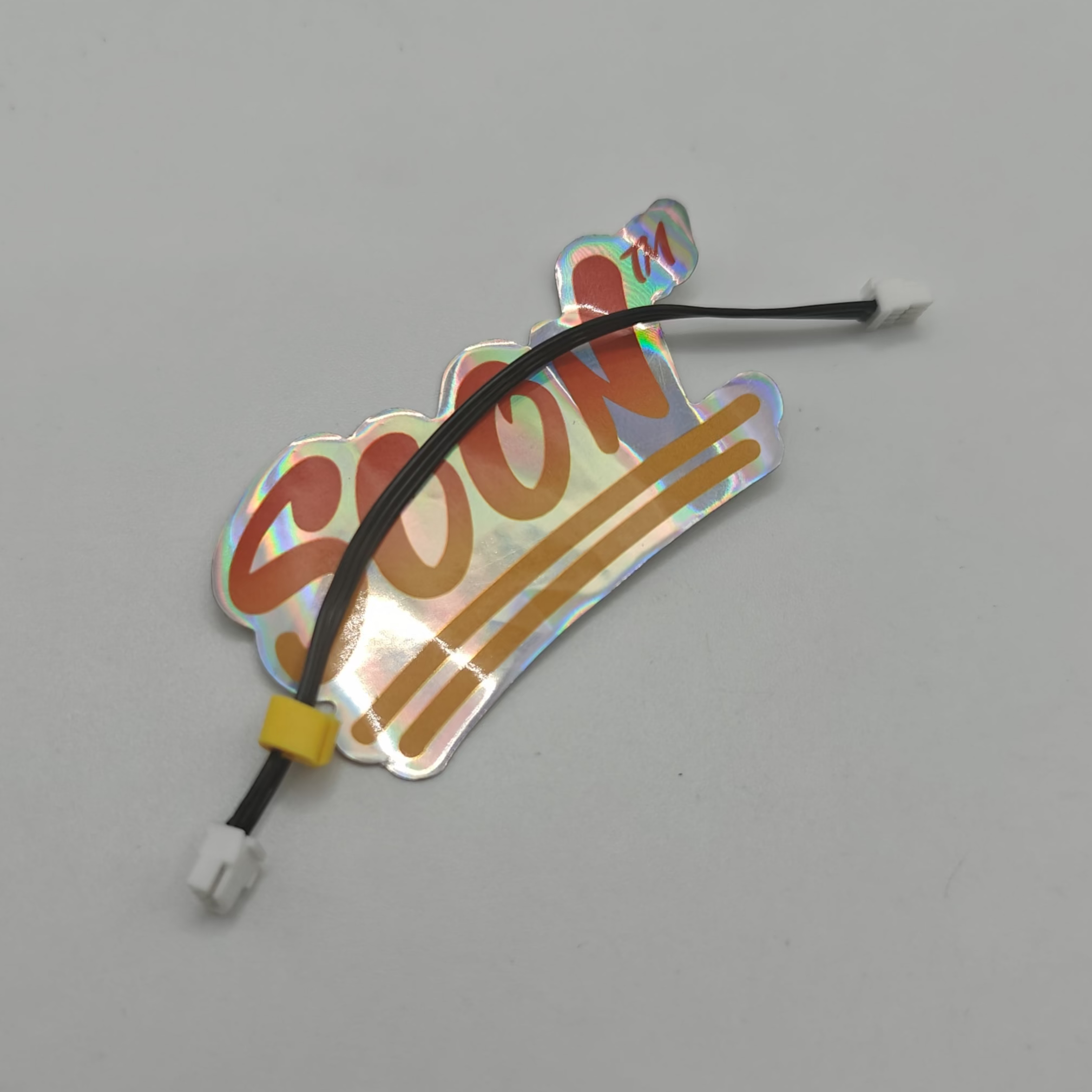 Holographic 'Soon' label with a black wire on a gray background