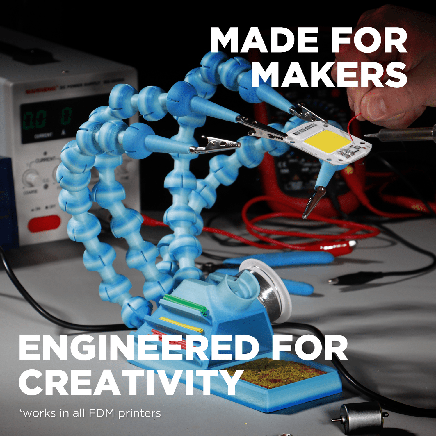 3D printing nozzle with blue flexible hose on a workbench, surrounded by tools and equipment.